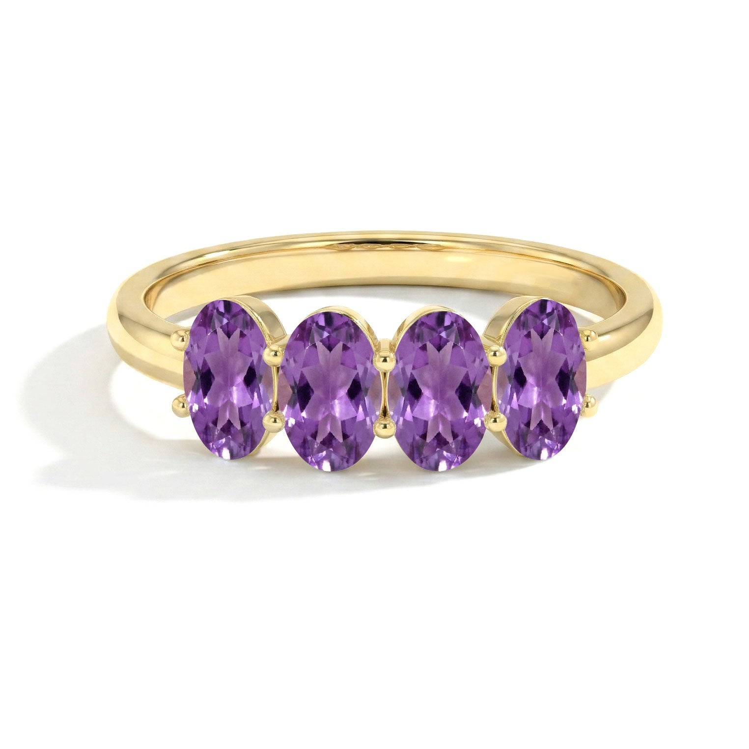 A yellow gold ring featuring four oval-cut purple amethyst gemstones set in a row on a white background.