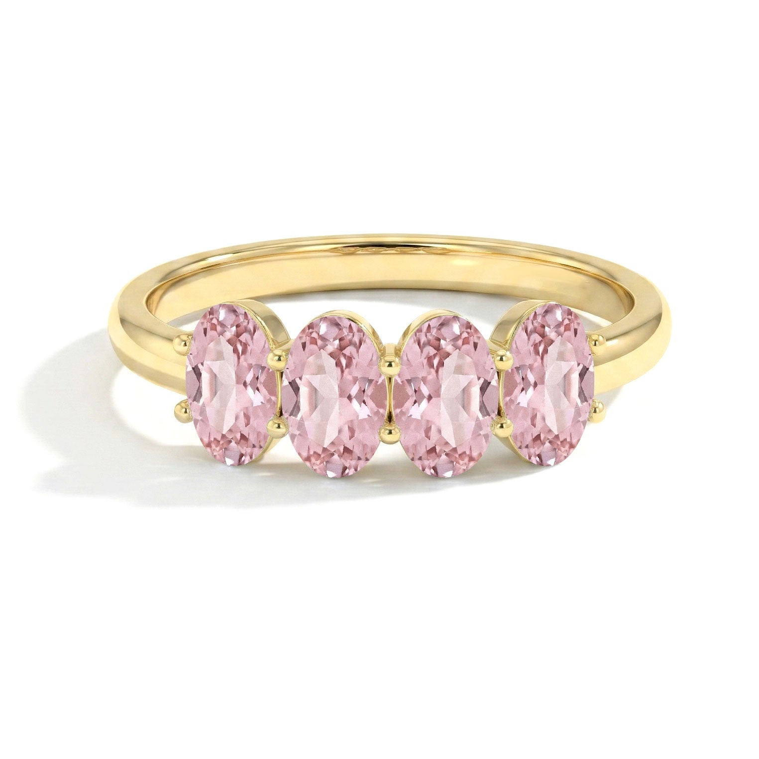 A yellow gold ring featuring four oval-cut pink gemstones in a row, set against a clean white background.