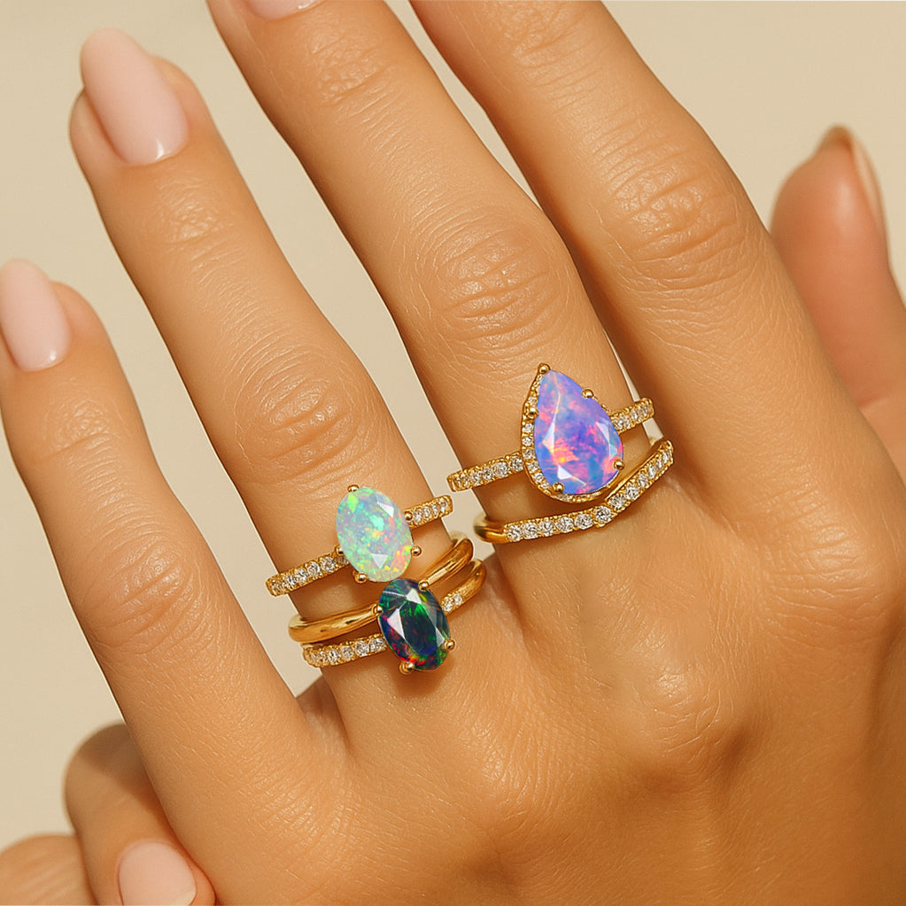 Woman’s hand wearing multi opal gemstone rings in gold band – luxury opal jewelry