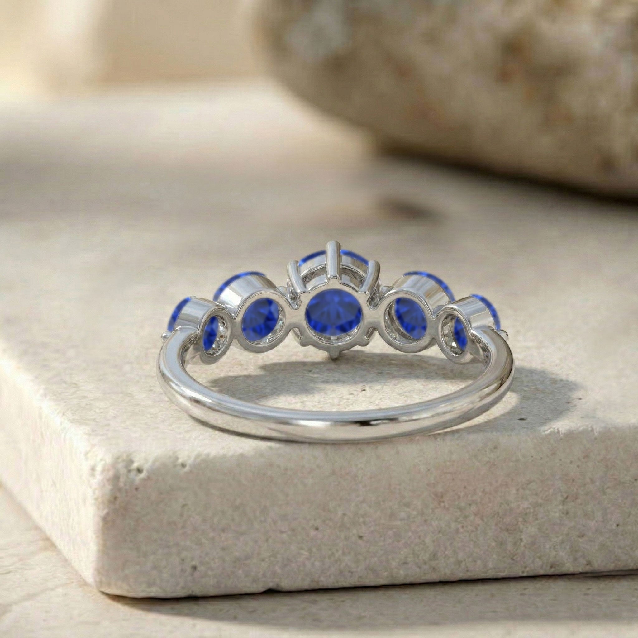 five sapphire stones, elegant blue ring, luxury birthstone jewelry, refined gemstone accessory, classic women's band, anniversary celebration gift, sparkling sapphire design, handcrafted elegance, stylish everyday ring, premium gemstone craftsmanship, stackable fashion jewelry, polished metal band, timeless sophistication, graceful accessory, designer inspired ring