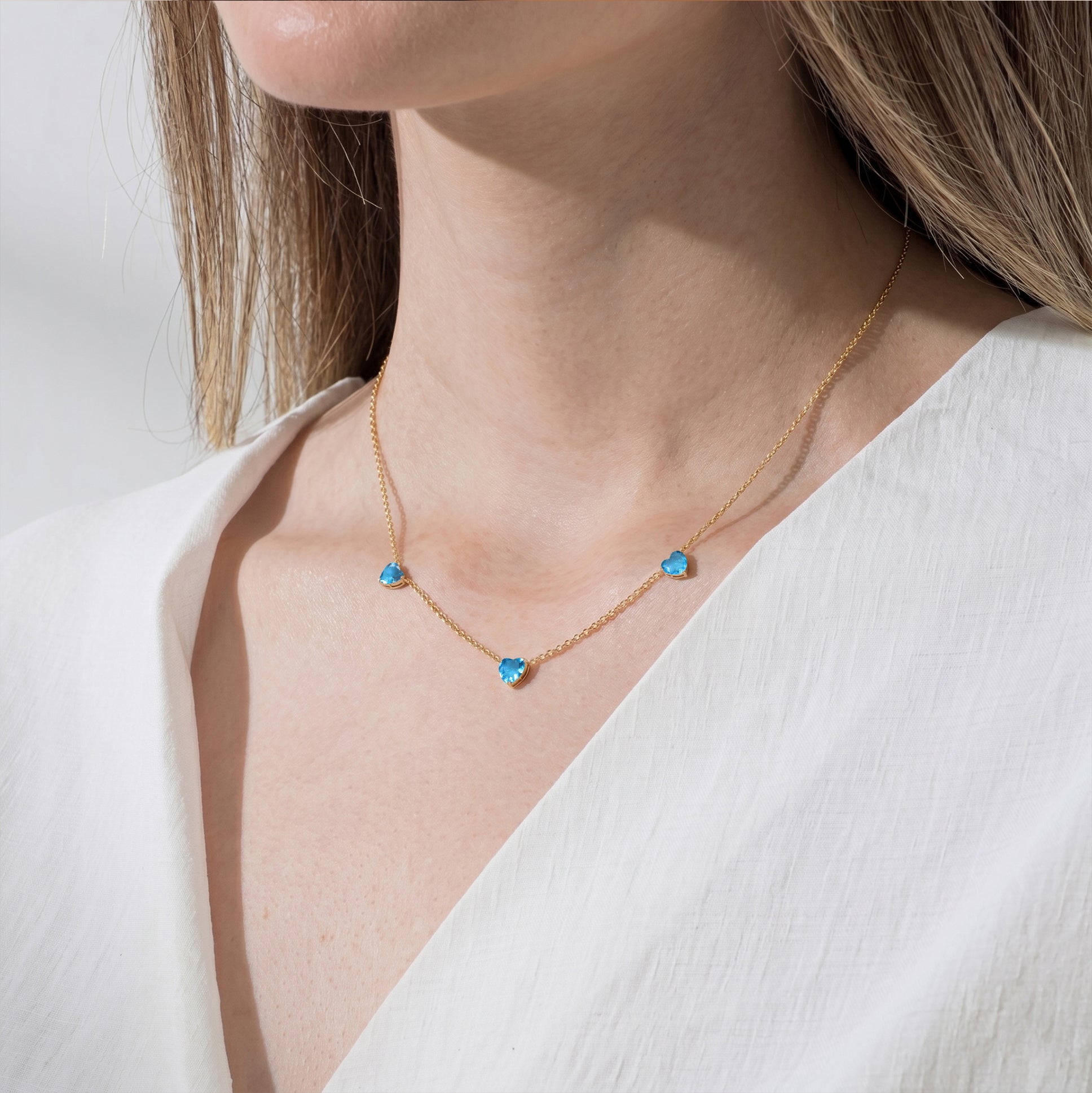 Rose Gold Filled Natural Blue Topaz Three Stone Heart Necklace with sparkling blue gemstones.
