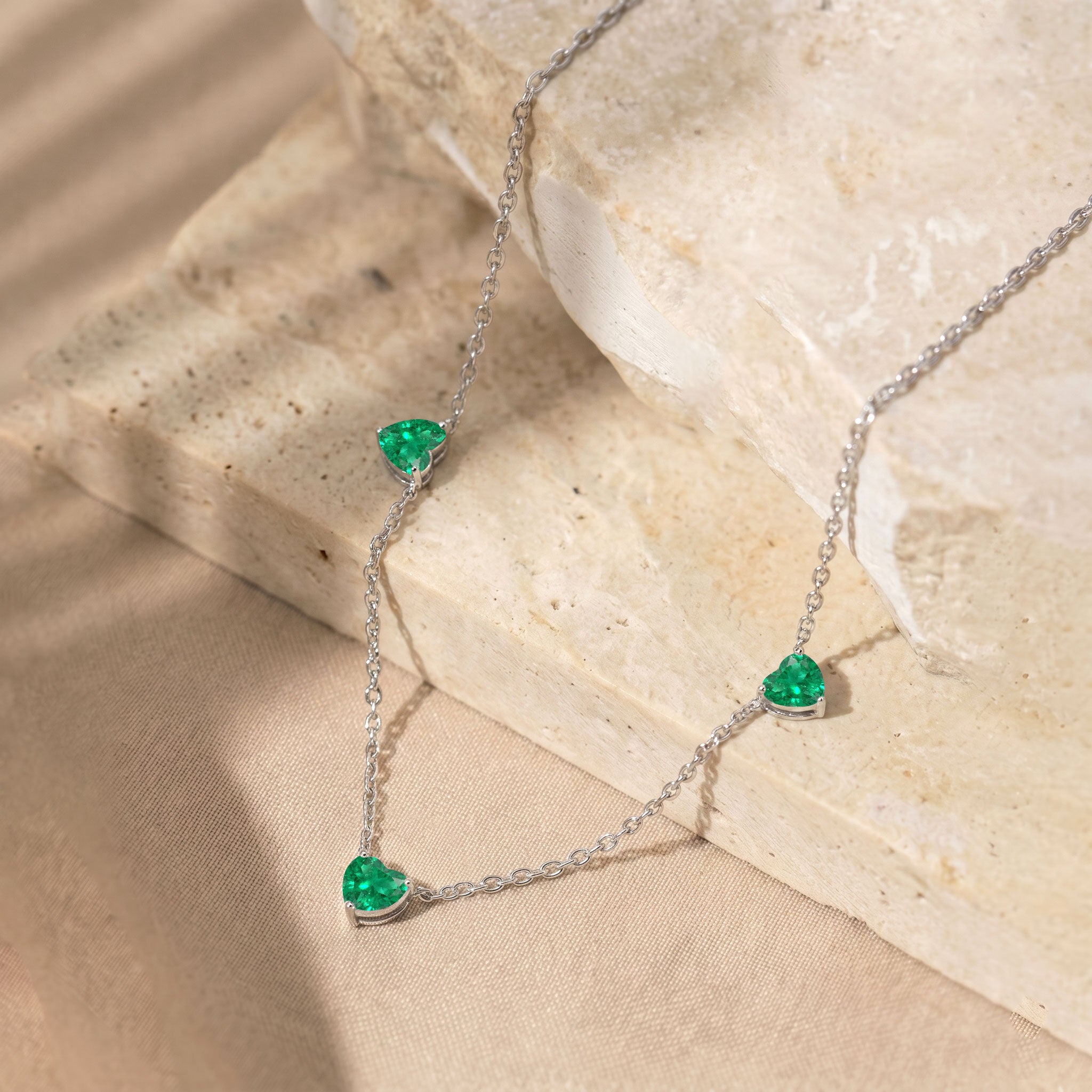 Elegant Emerald Three Stone Heart Necklace with genuine green gemstones.
