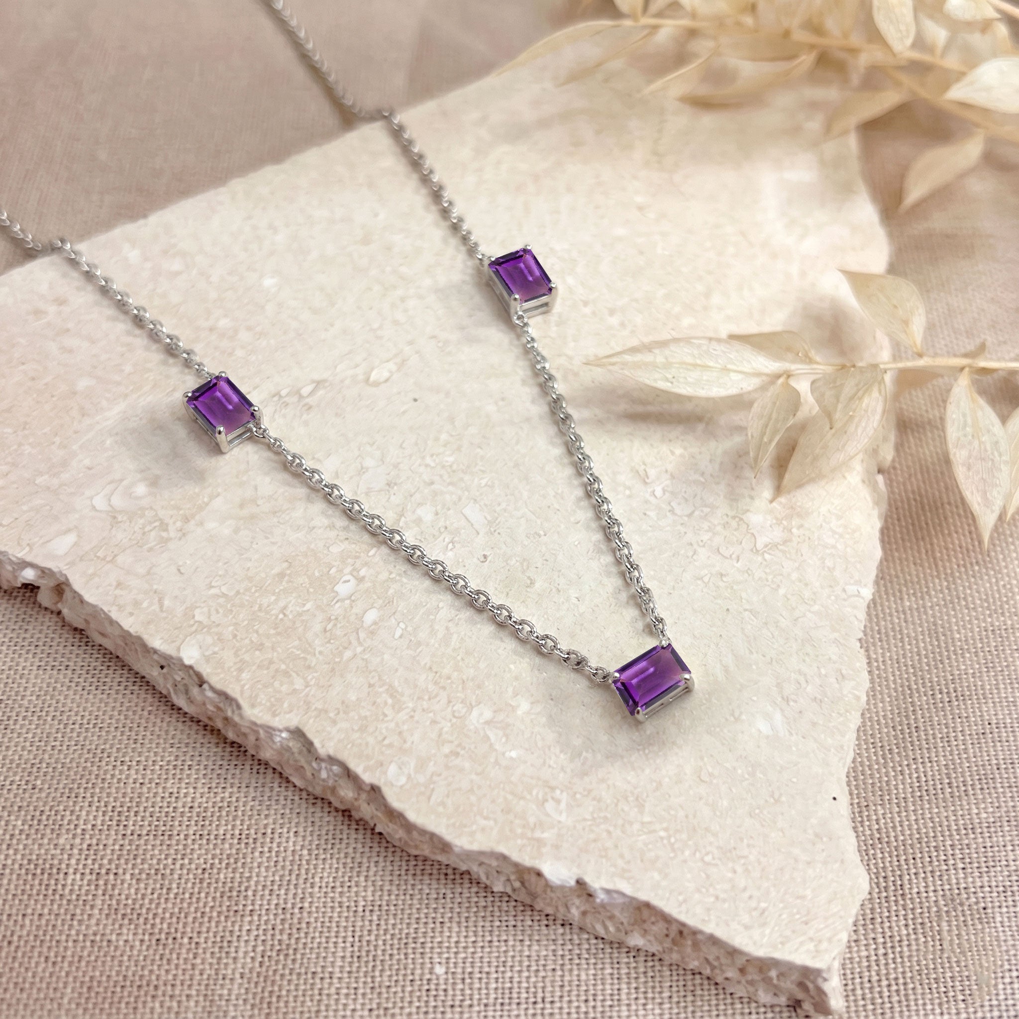Elegant three stone Amethyst necklace with octagon-cut purple gemstones.
