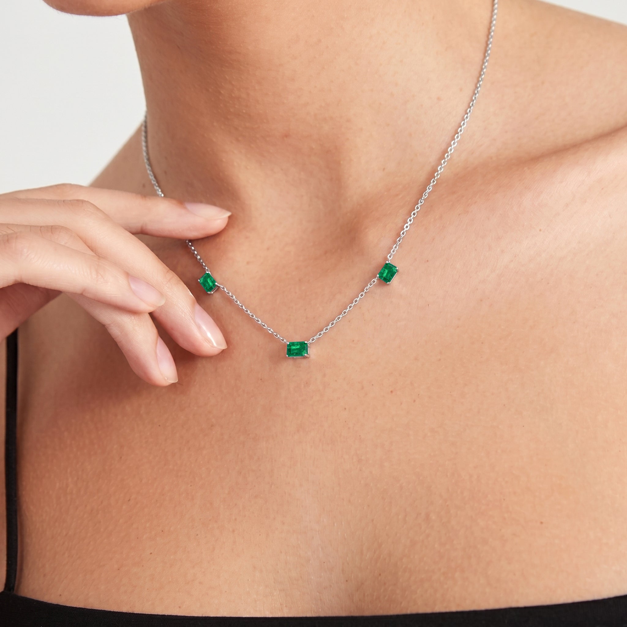 Fine jewelry Emerald station necklace with three octagon-cut gemstones.
