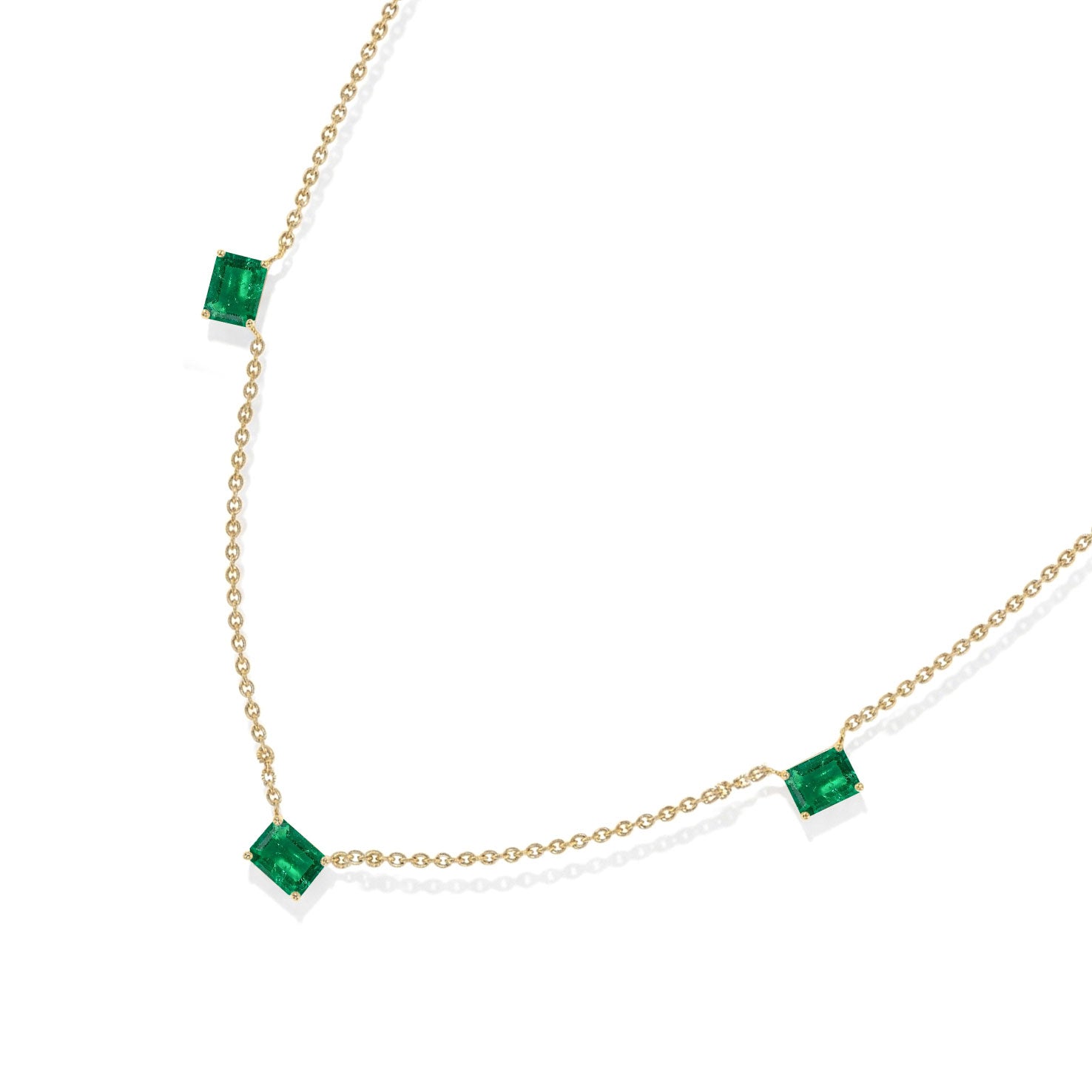 A delicate chain necklace featuring three small, square-cut emerald-cut green gemstones spaced along the chain, displayed on a clean white background.
