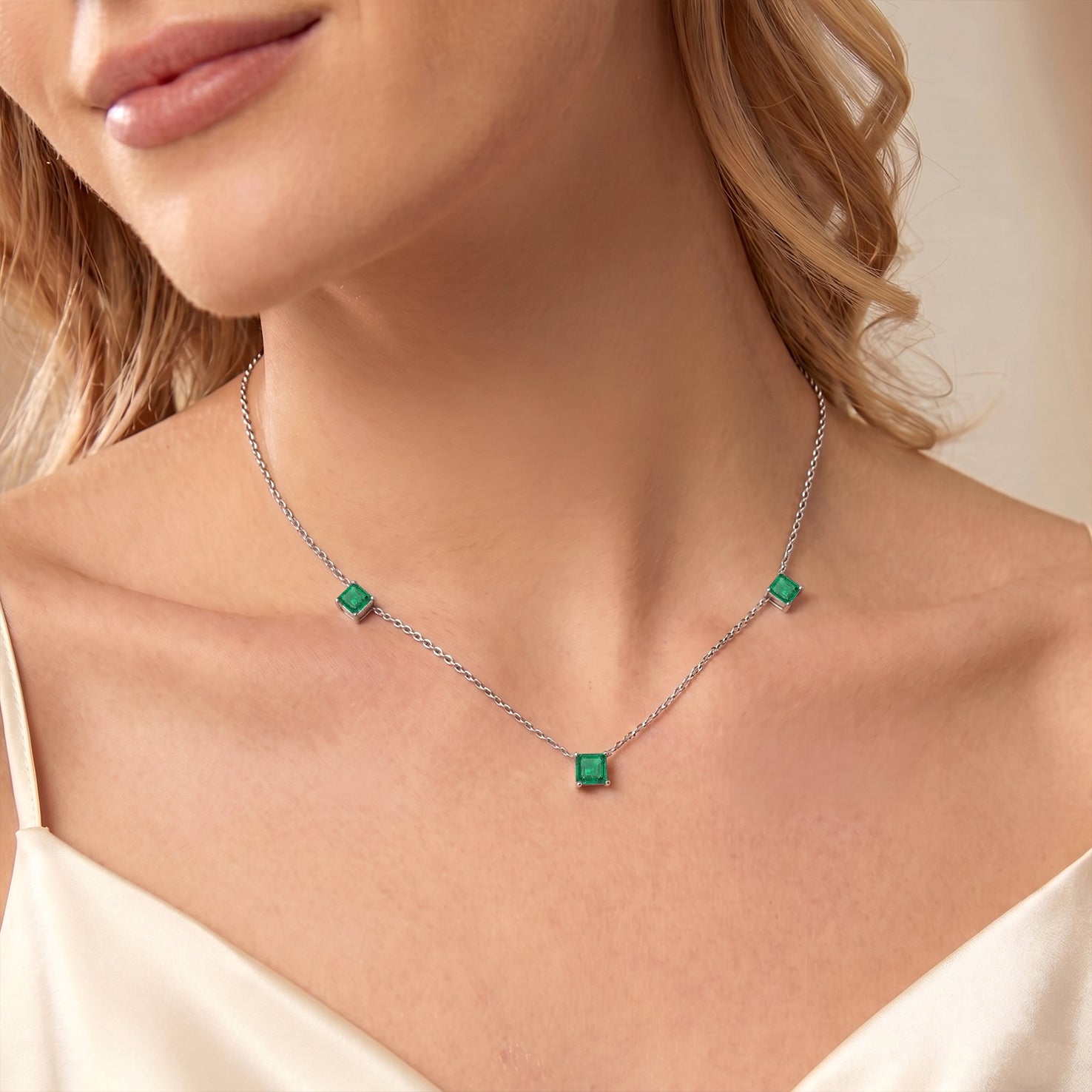 Dainty Emerald station necklace featuring three Asscher cut gemstone accents.
