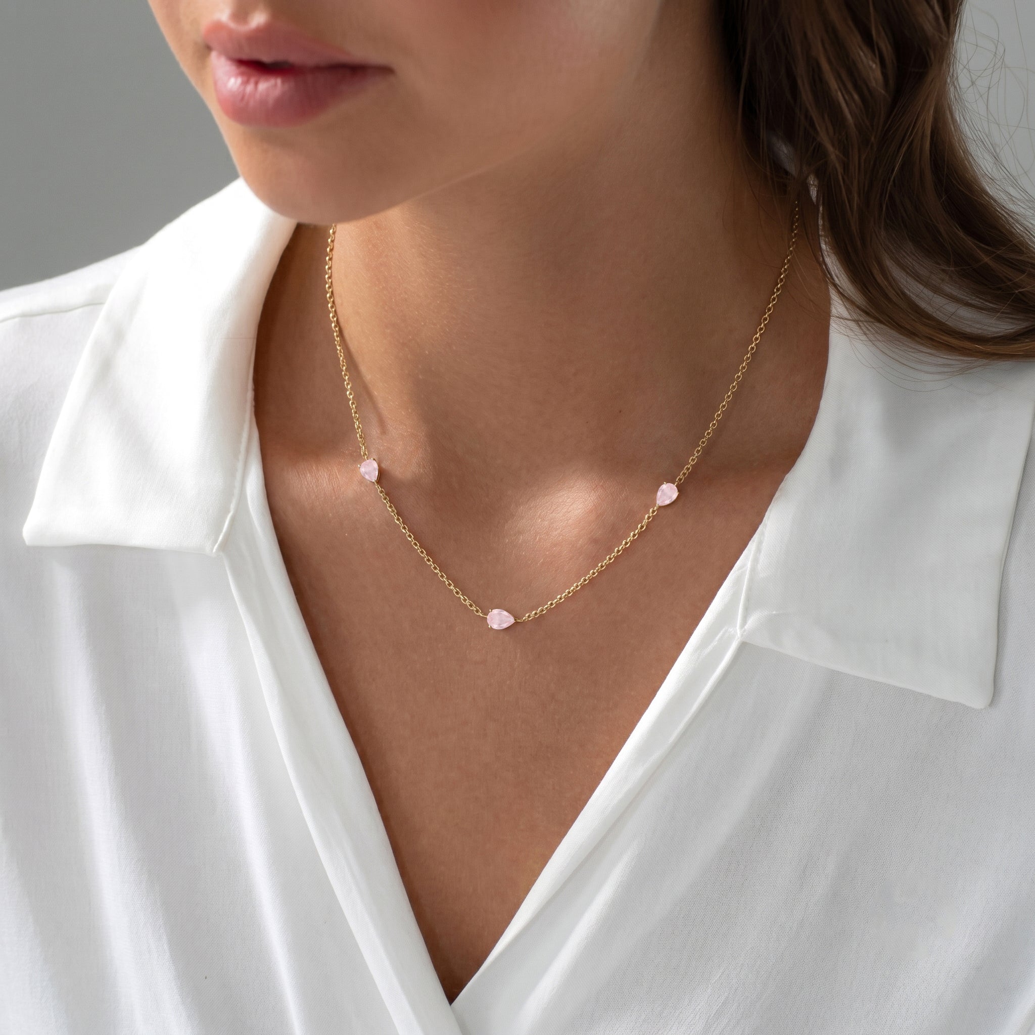 Three pear-shaped rose quartz gemstone necklace with elegant station setting and adjustable chain.
