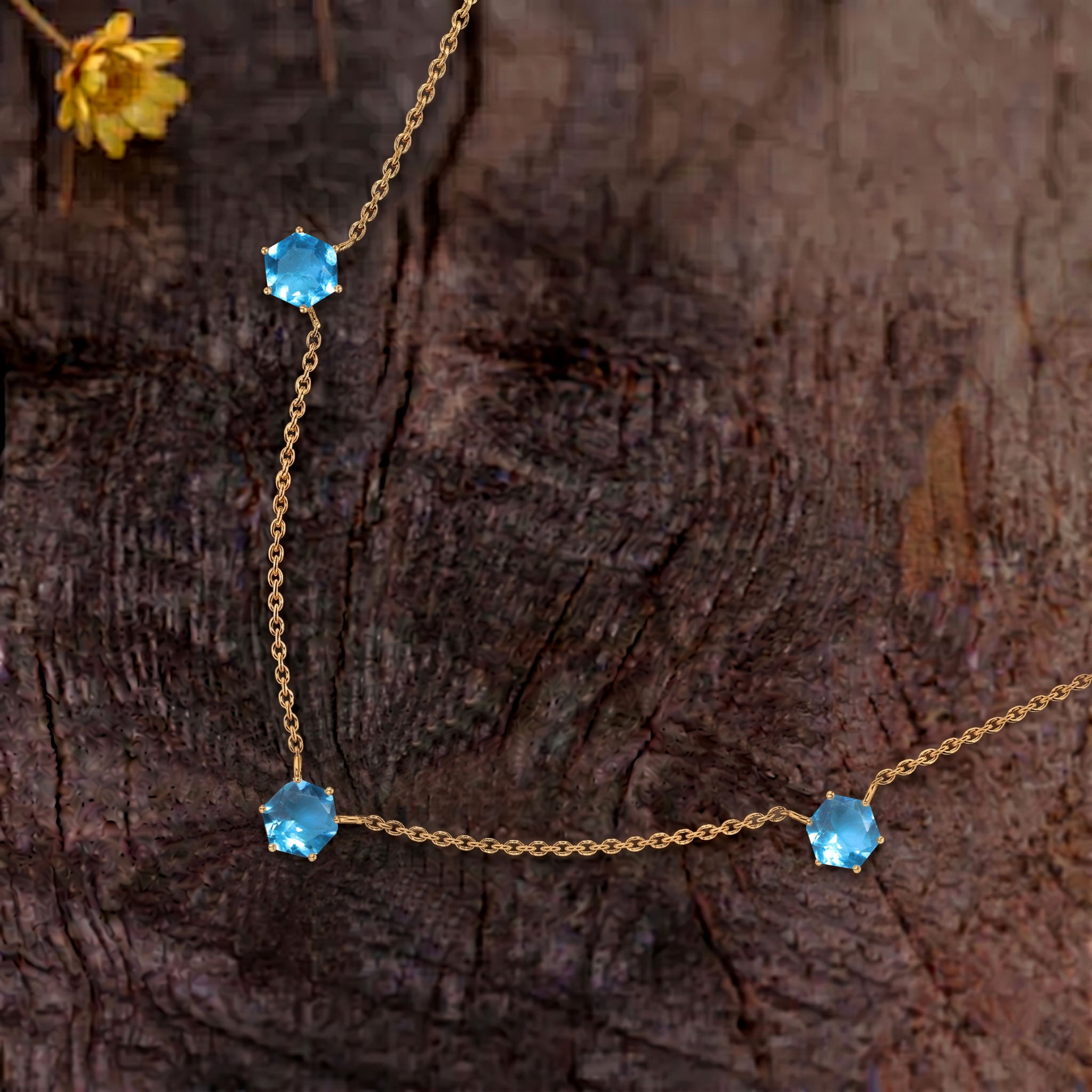 Close up view of three hexagon cut blue topaz gemstones on elegant necklace design
