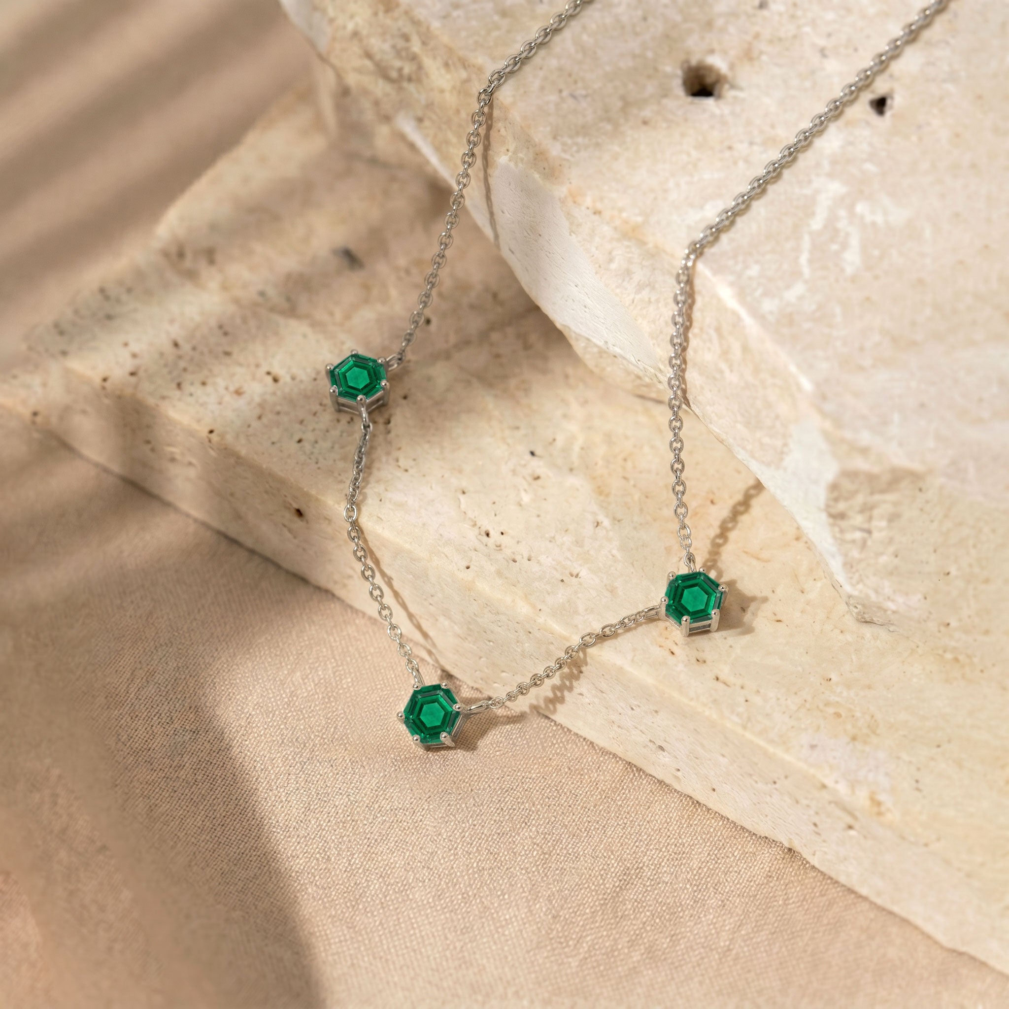 Sophisticated three stone emerald jewelry piece featuring geometric gemstone accents
