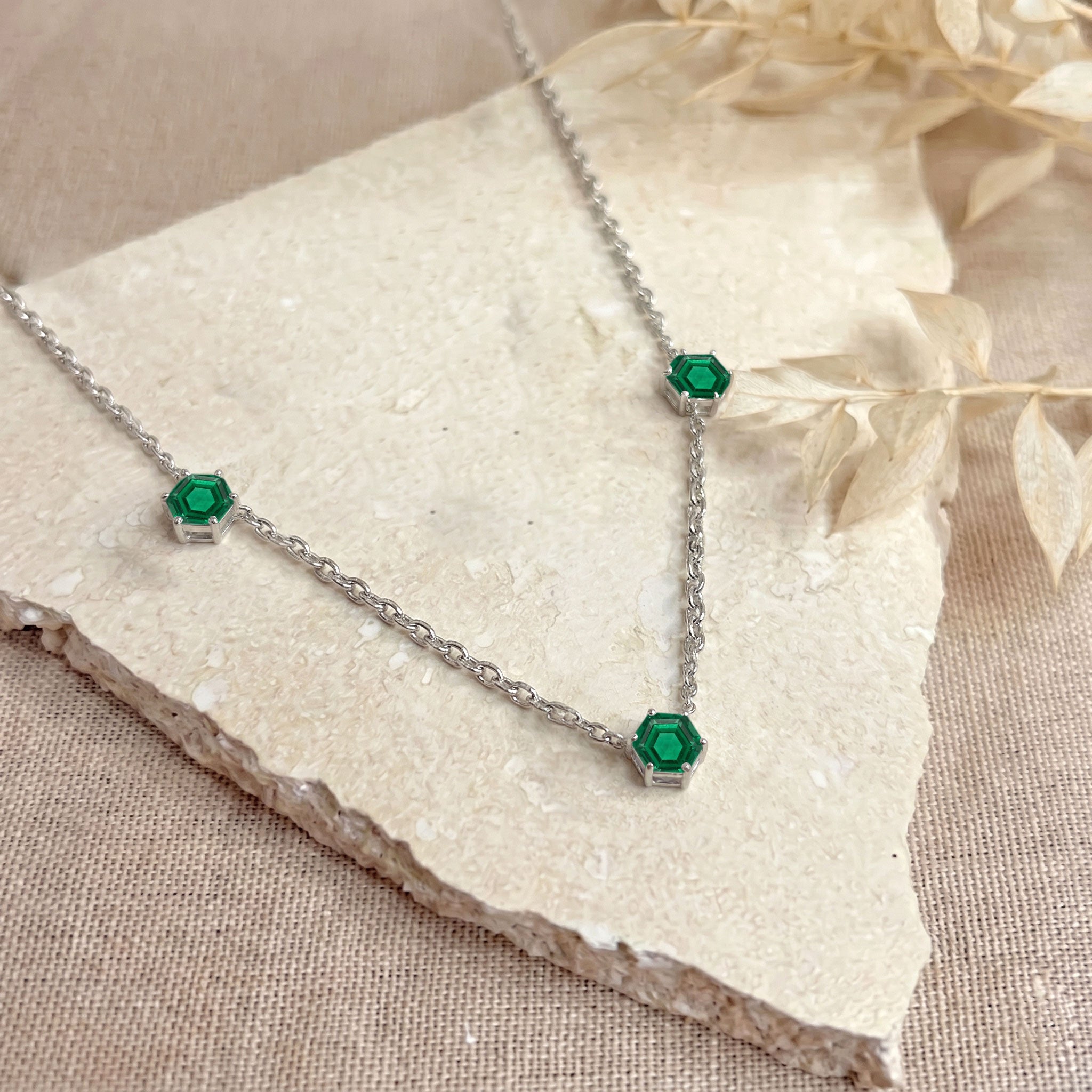 Contemporary emerald necklace featuring three faceted gemstones in a minimalist station style
