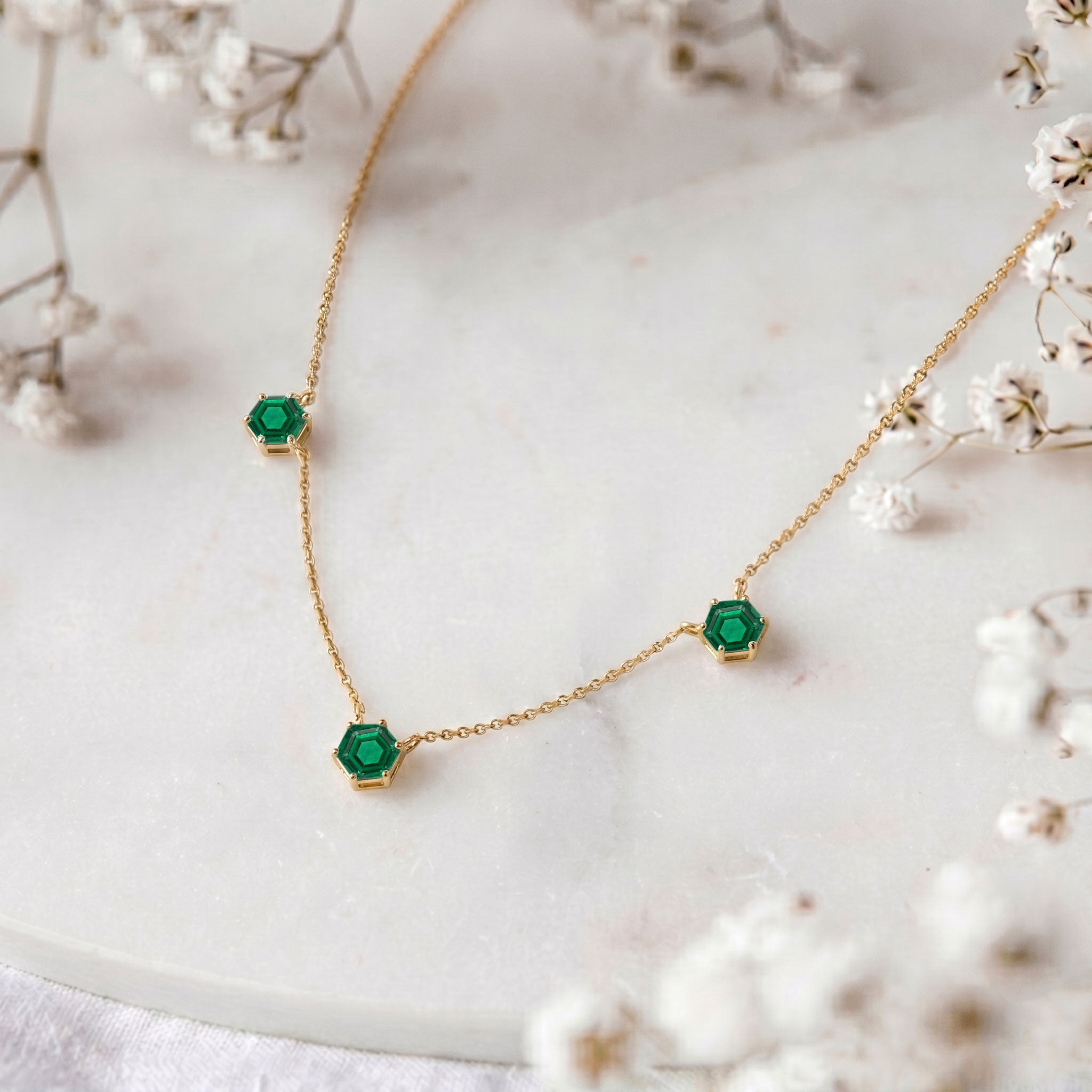 Refined emerald fine jewelry necklace designed with three gemstone stations and silver setting
