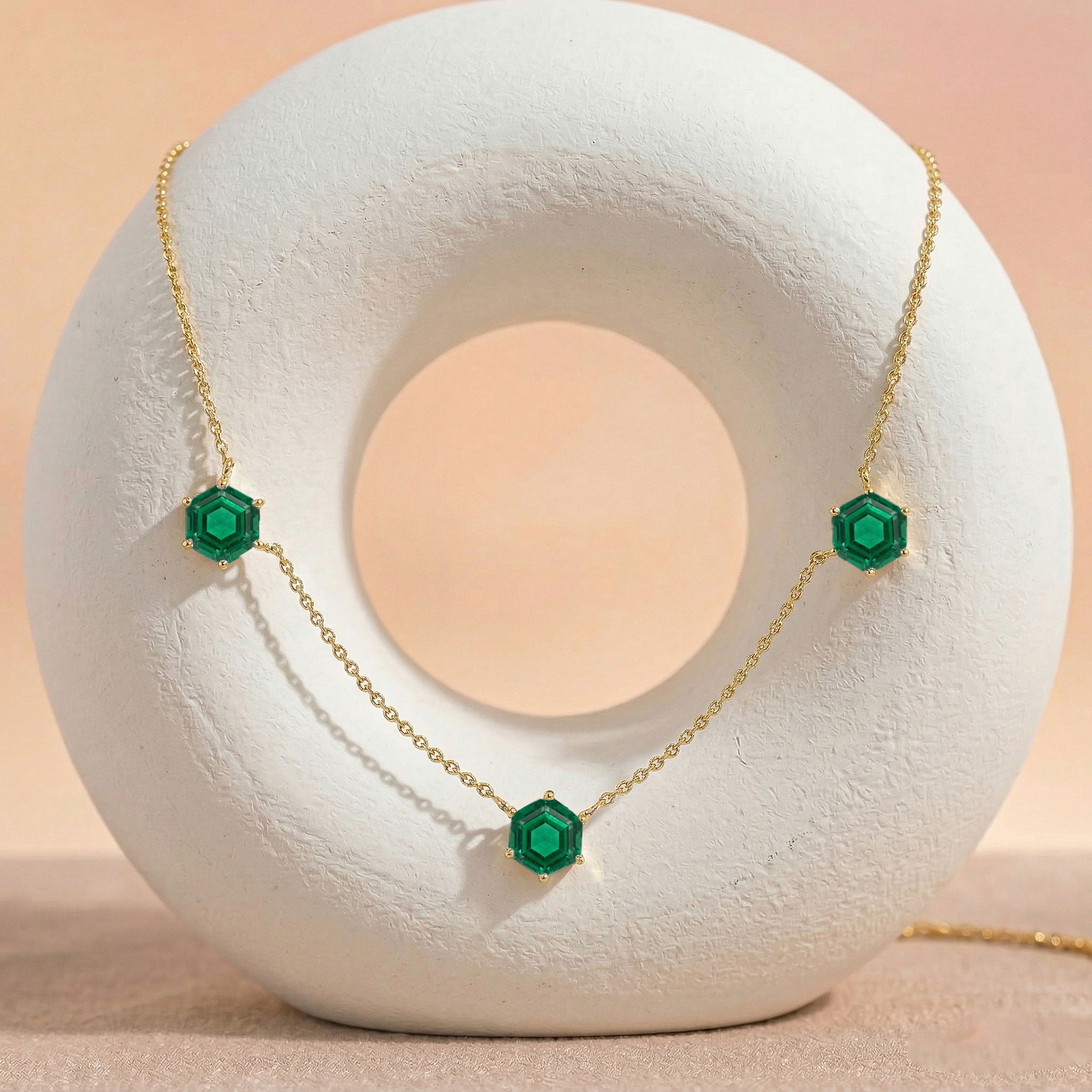 Modern gemstone jewelry necklace featuring emerald stones, sterling silver, and gold finish
