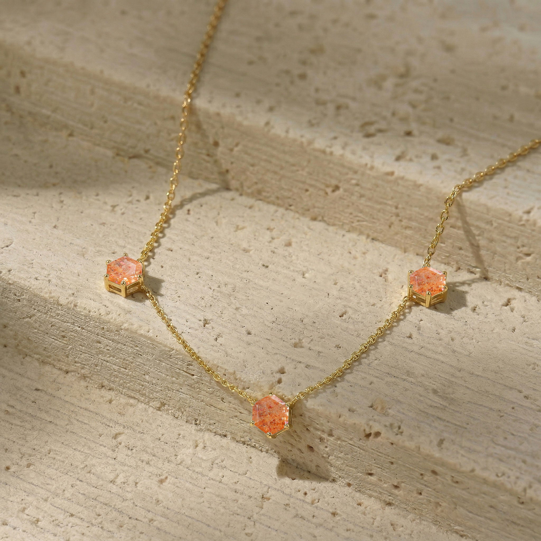 Close up view of three hexagon cut sunstone gemstones on elegant necklace design
