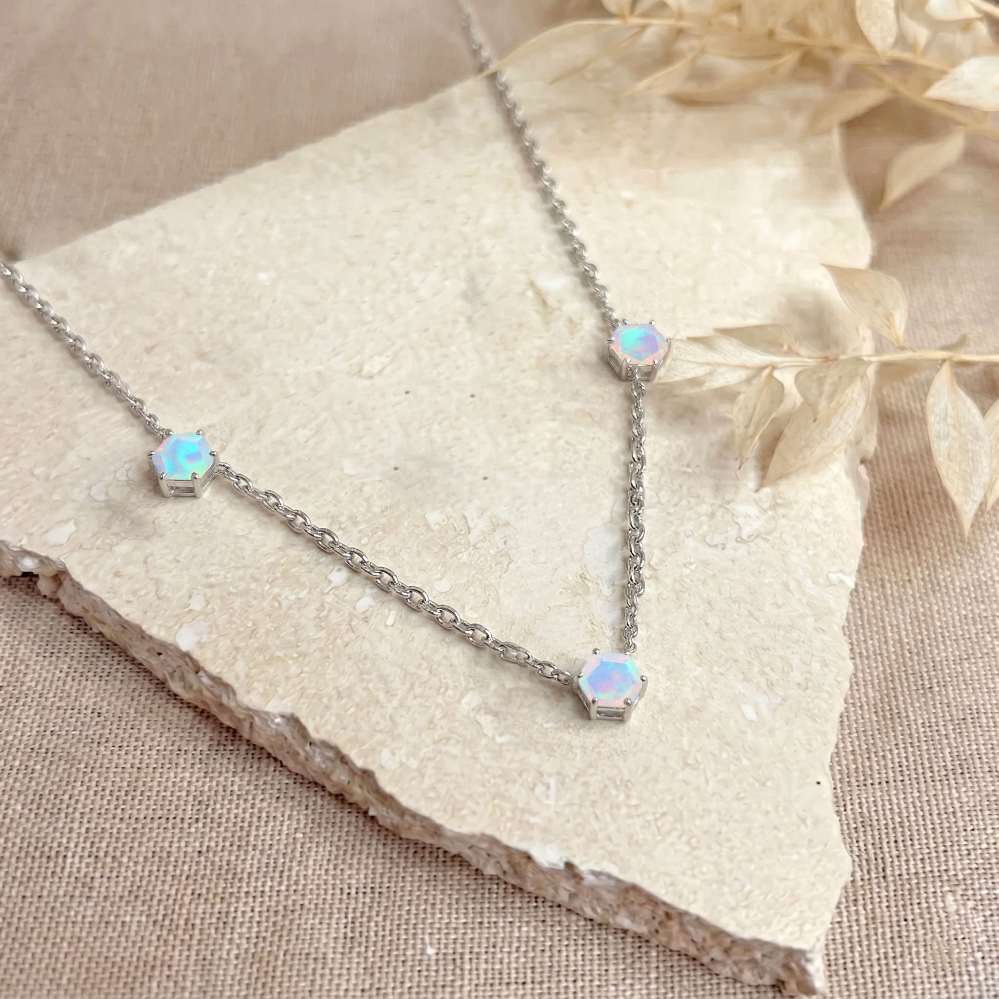 
Close-up view of hexagon White Opal gemstones on a delicate necklace.

