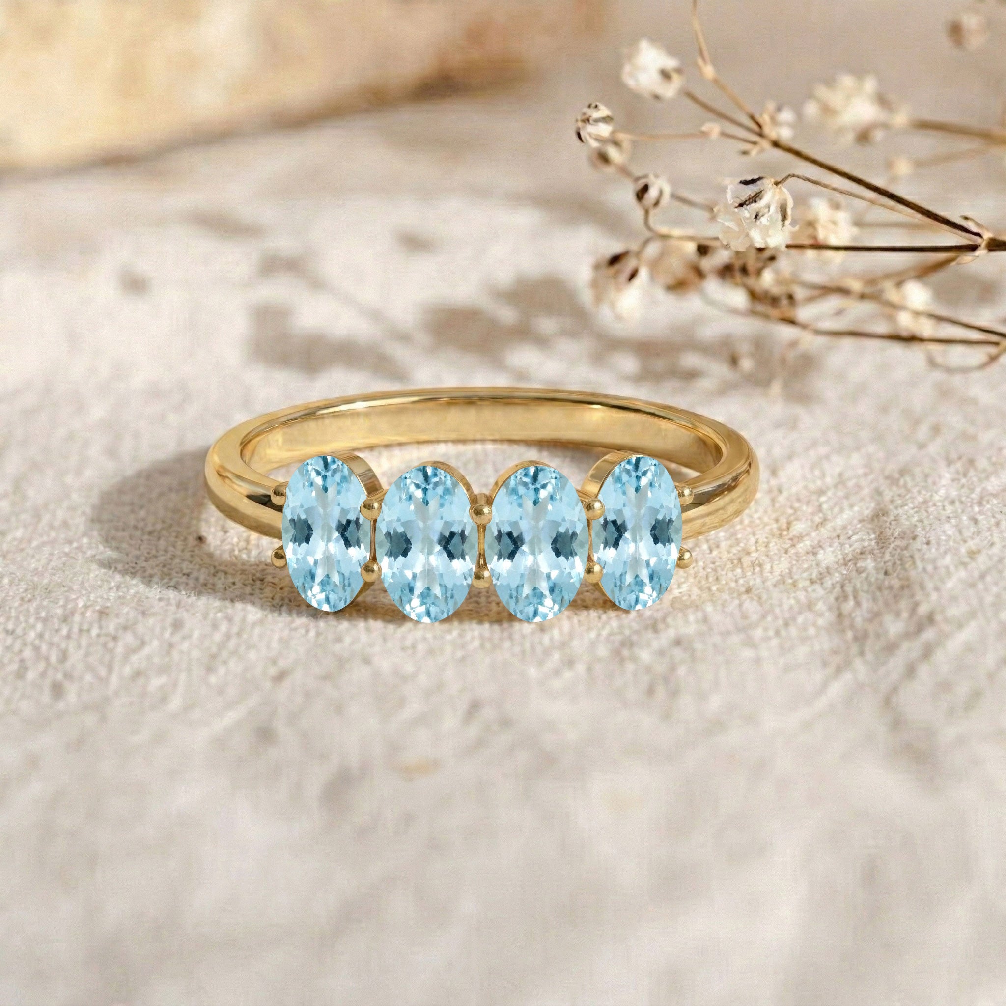 aquamarine anniversary ring, four stone jewelry, oval gemstone design, sophisticated ring, elegant blue gemstone, bridal accessory, luxury fashion jewelry, handmade ring, refined craftsmanship, modern band, classic elegance, meaningful gift