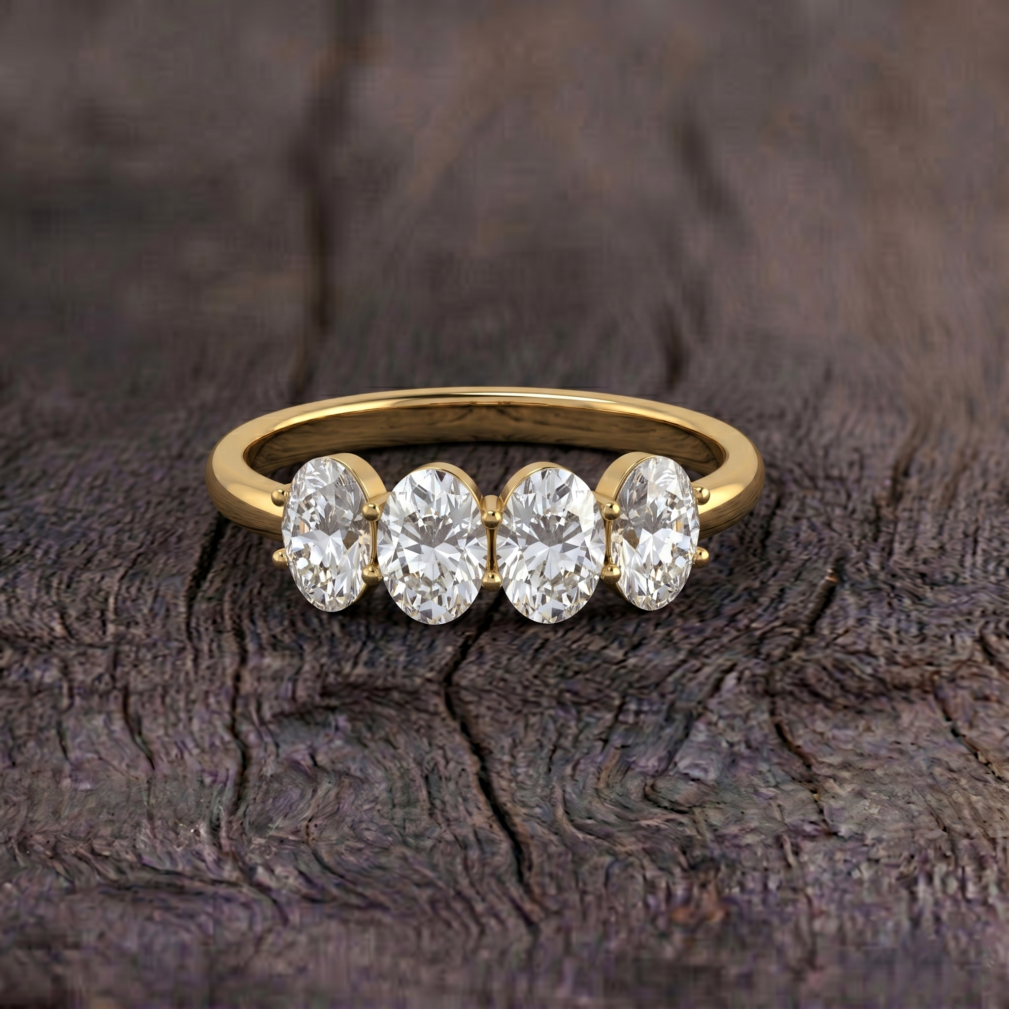 A yellow gold ring with four oval-cut clear gemstones, displayed on a dark textured wood surface.