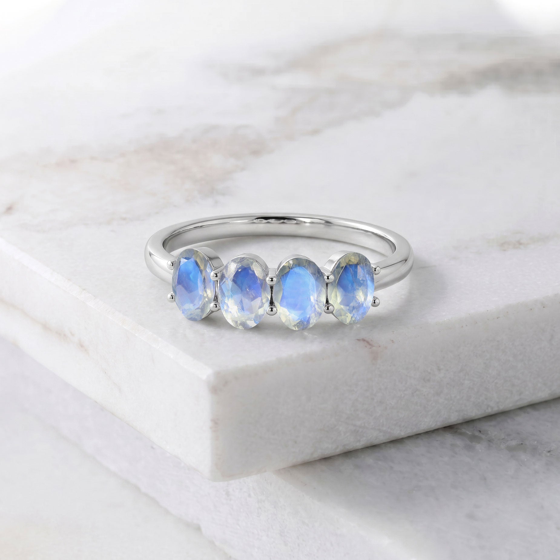 Moonstone Ring styled on marble background with luxury accessories, genuine natural moonstones, blue flash gemstone jewelry, handcrafted 925 Sterling Silver ring, elegant stackable ring, fine artisan craftsmanship, June birthstone jewelry, premium fashion accessory, sophisticated minimalist jewelry, timeless luxury ring for women with polished finish