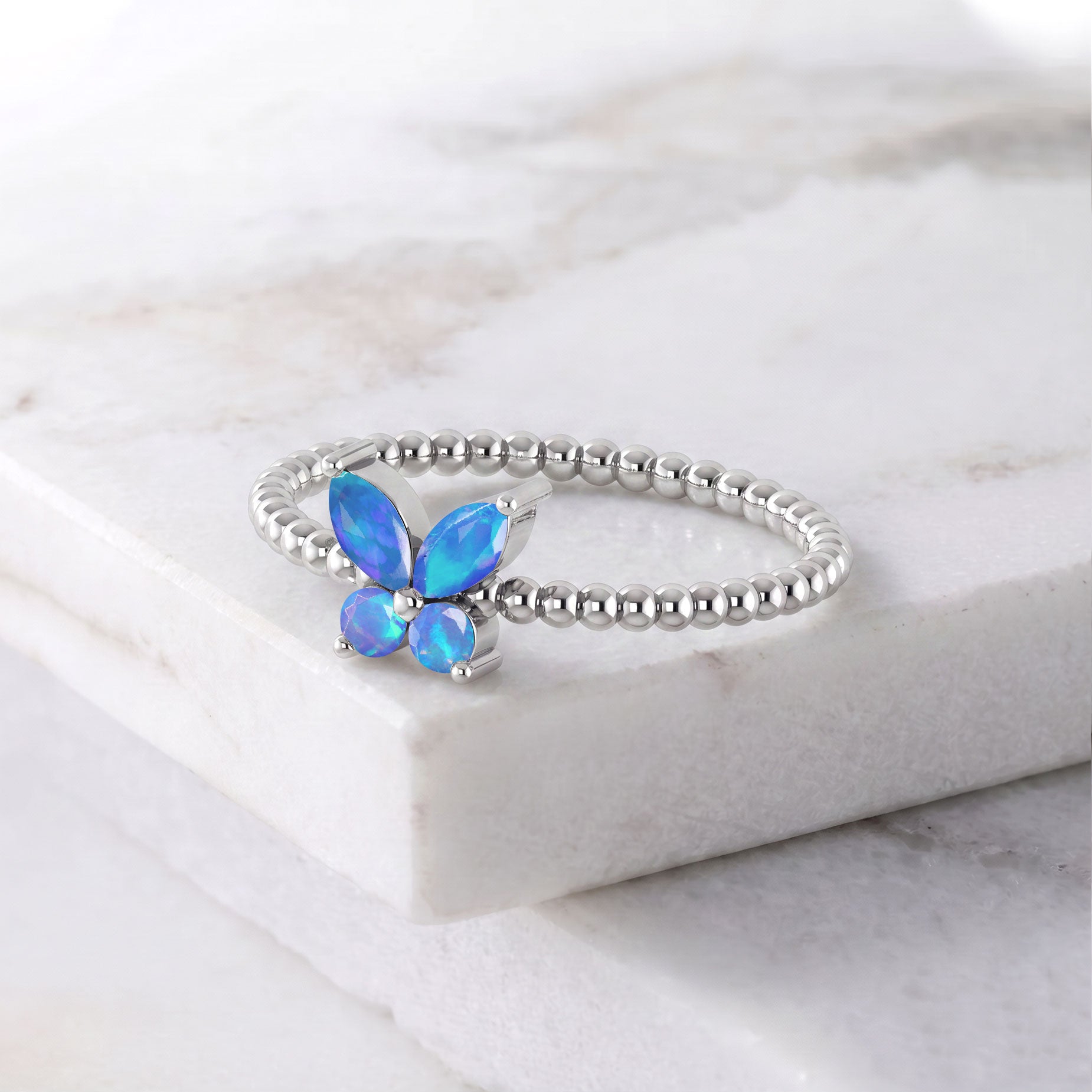 Natural blue opal marquise butterfly ring featuring vibrant iridescent blue gemstones, two round opal accents, and an elegant polished metal setting