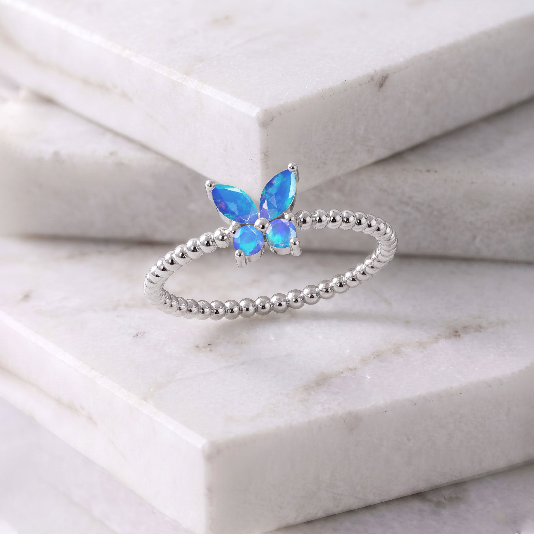 Natural blue opal statement butterfly ring featuring luminous blue gemstone wings, two round opal stones, and an elegant beaded sterling silver band